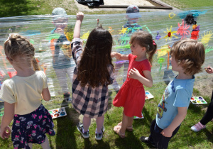 Dzieci w ogrodzie malują na folii, na pierwszym planie dworo dzieci